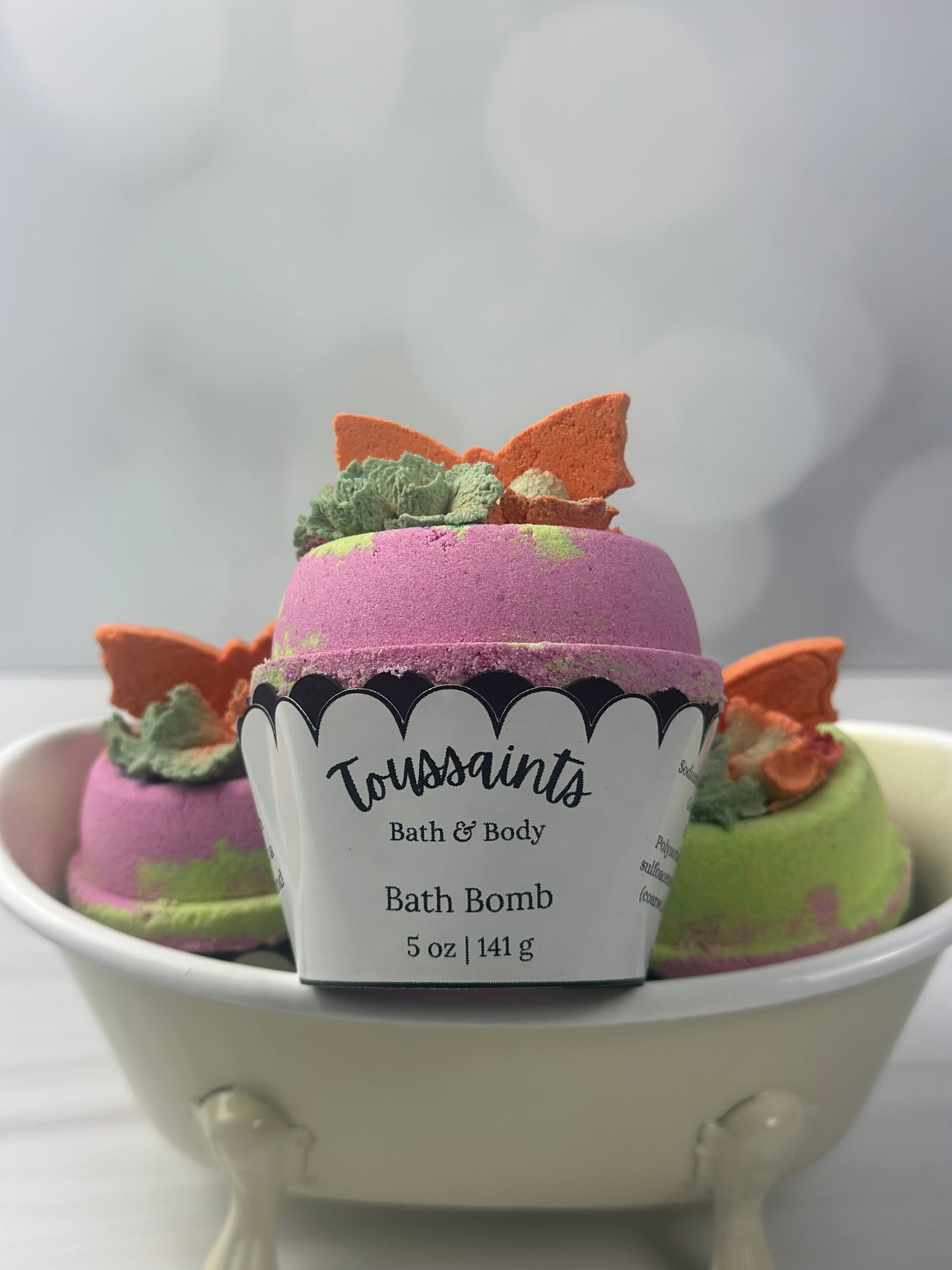Pink bath bomb with orange butterfly sitting inside Cupcake holder